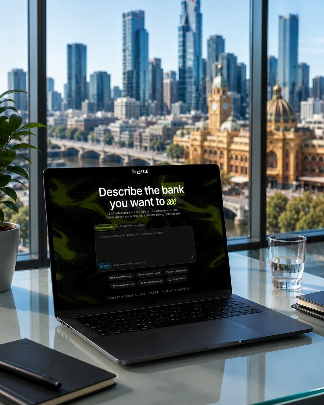 A laptop on a desk showing the Kobble product, with a Melbourne city skyline beyond.